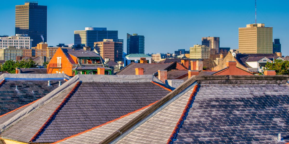 Rooftop view of New Orleans buildings, with historic homes and modern skyscrapers in the background.