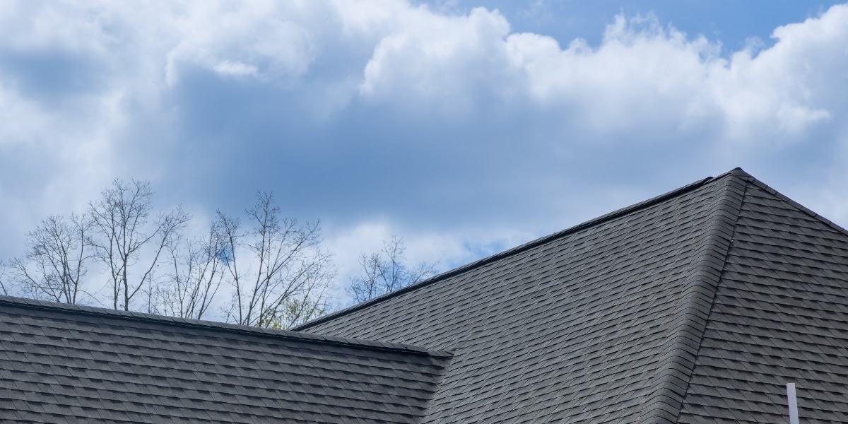 A close-up view of an impact-resistant shingle roof under a cloudy sky, showcasing its durability and design for weather protection in New Orleans.