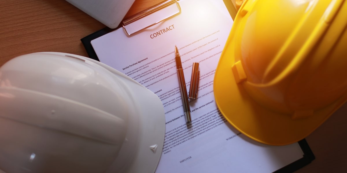 A contract document placed on a wooden table with two pens and construction helmets, symbolizing safety and professionalism in the roofing industry.