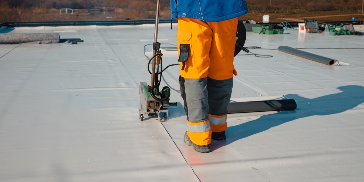 Worker insulating a commercial roof to improve energy efficiency and protect Louisiana businesses from extreme weather.